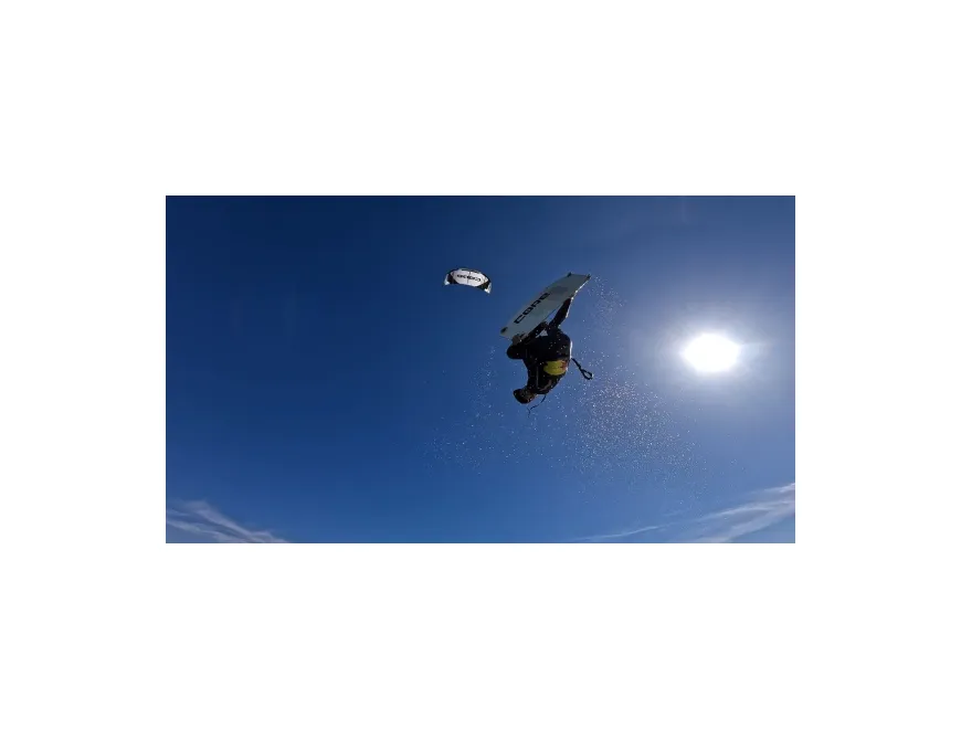 Advanced kitesurf jump under a clear blue sky during a clinic with IKO instructor